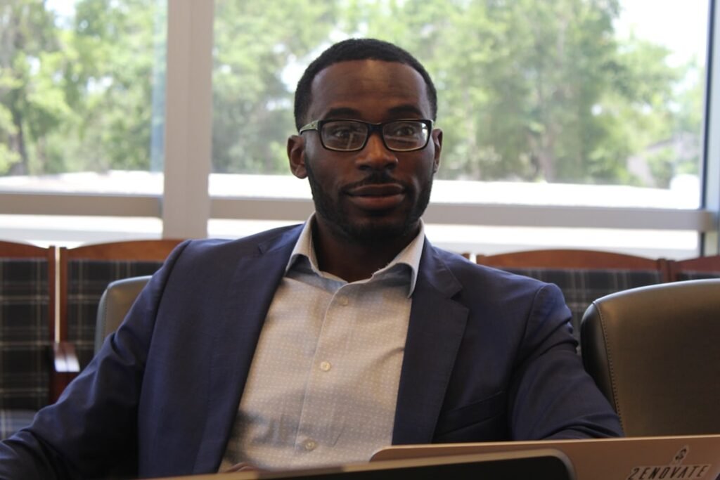 Xavier Pavie standing in a modern academic library setting, wearing professional attire, looking thoughtful
